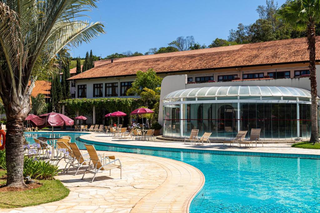 Vista da piscina do Villa di Mantova Resort Hotel durante o dia com cadeiras em volta da piscina. Representa Águas de Lindóia.