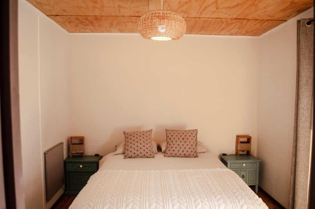 Quarto do Eco-Hostal Tambo Verde com cama de casal no meio do quarto com duas cômodas de madeira verde em cada lado da cama.