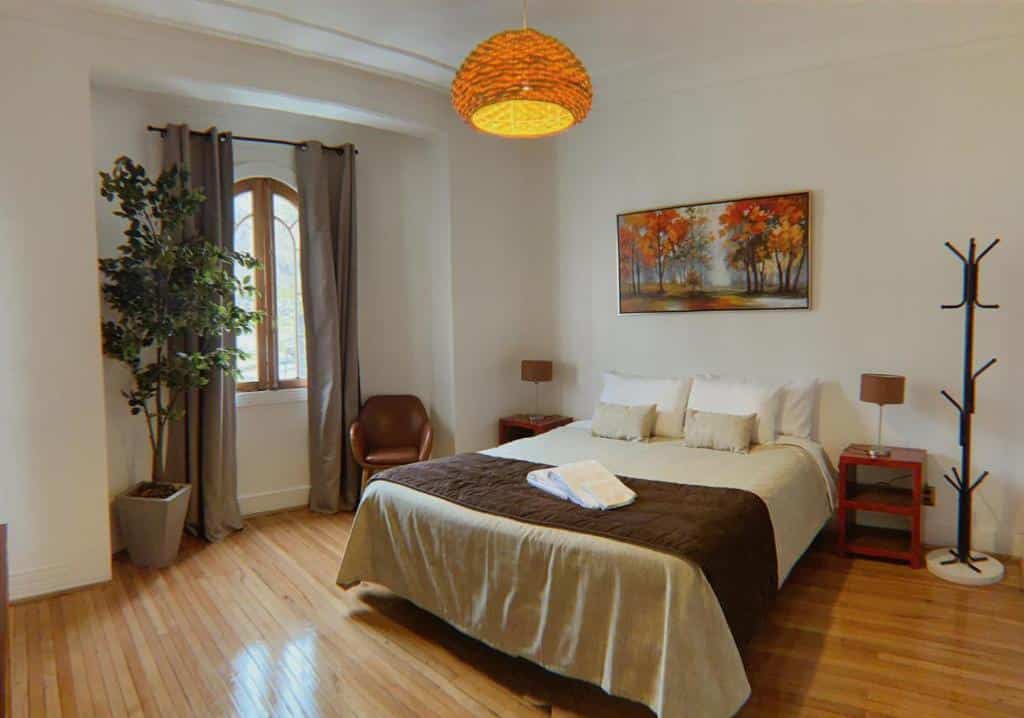 Quarto do Hotel De Blasis & Cowork com cama de casal no centro do quarto com duas cômodas de madeira ao lado da cama.