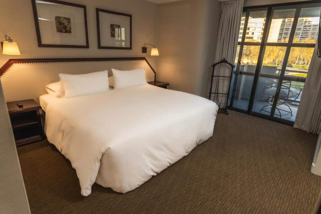 Quarto do Hotel Kennedy com cama de casal no centro do quarto com duas cômodas de madeira ao lado da cama.