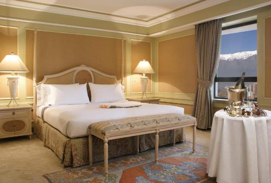 Quarto do Hotel Regal Pacific com cama de casal do lado esquerdo e em frente a cama uma mesa redonda com toalha branca e um balde com champanhe.
