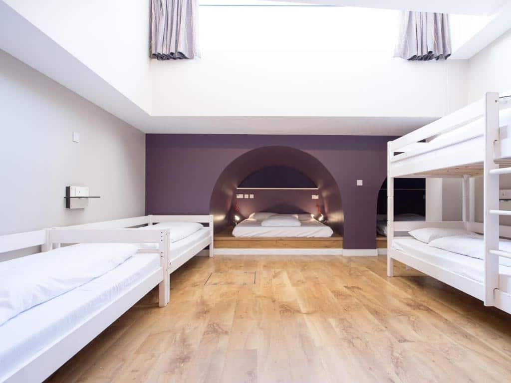 Uma espaço amplo no Wombat’s City Hostel London com duas beliches, duas camas de solteiro, e camas de casal no chão de madeira