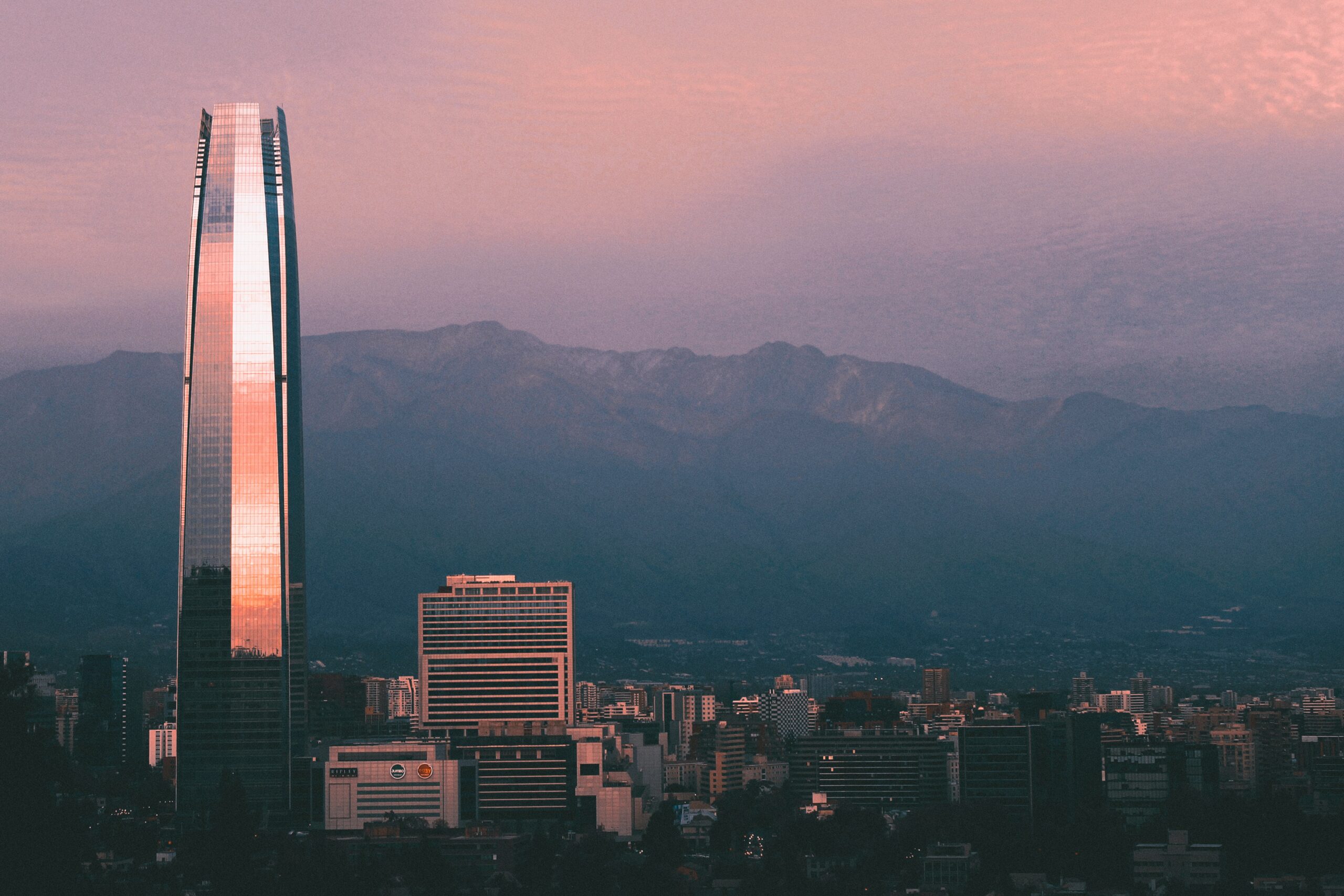 Vista do Sky Costanera, Santiago, Chile durante o dia com prédio enorme em volta de outros edifícios.