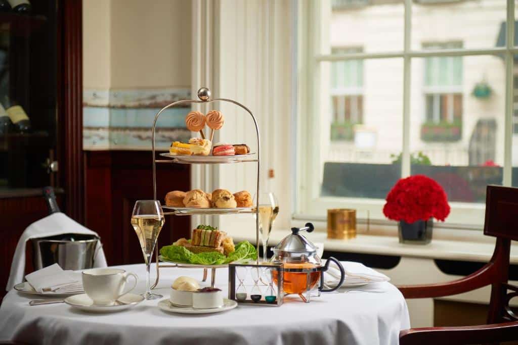 Uma mesa no The Montague On The Gardens com pães, sanduíches, taças com champanhe e chás, para representar hotéis boutique em Londres