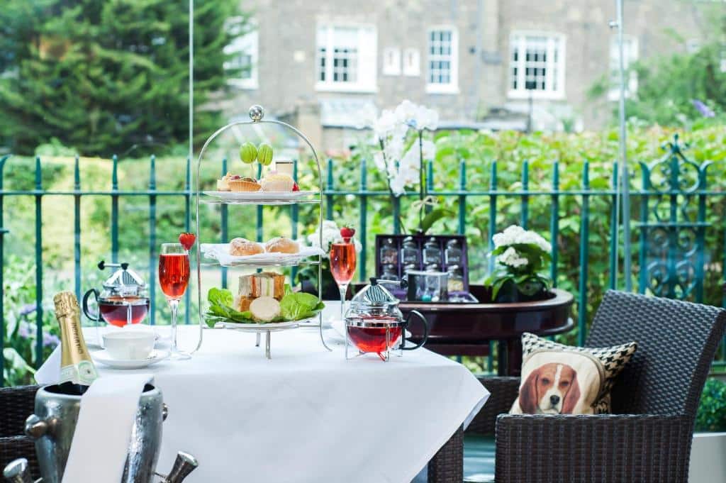 Espaço aberto  do The Montague On The Gardens com mesas quadradas com peticos e chás em cima, com vista para o jardim, para representar hotéis bem localizados em Londres