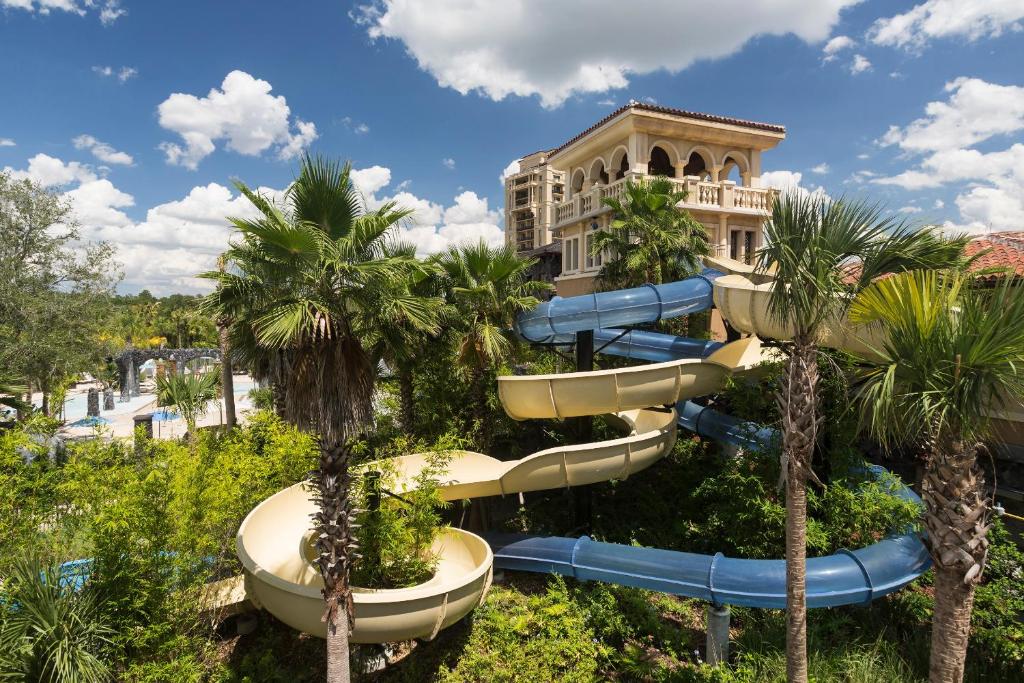 tobogã grande e sinuoso azul e branco em meio à natureza, com a estrutura do Four Seasons Resort Orlando at Walt Disney World Resort, em Orlando, atrás com diversas janelinhas e céu azul