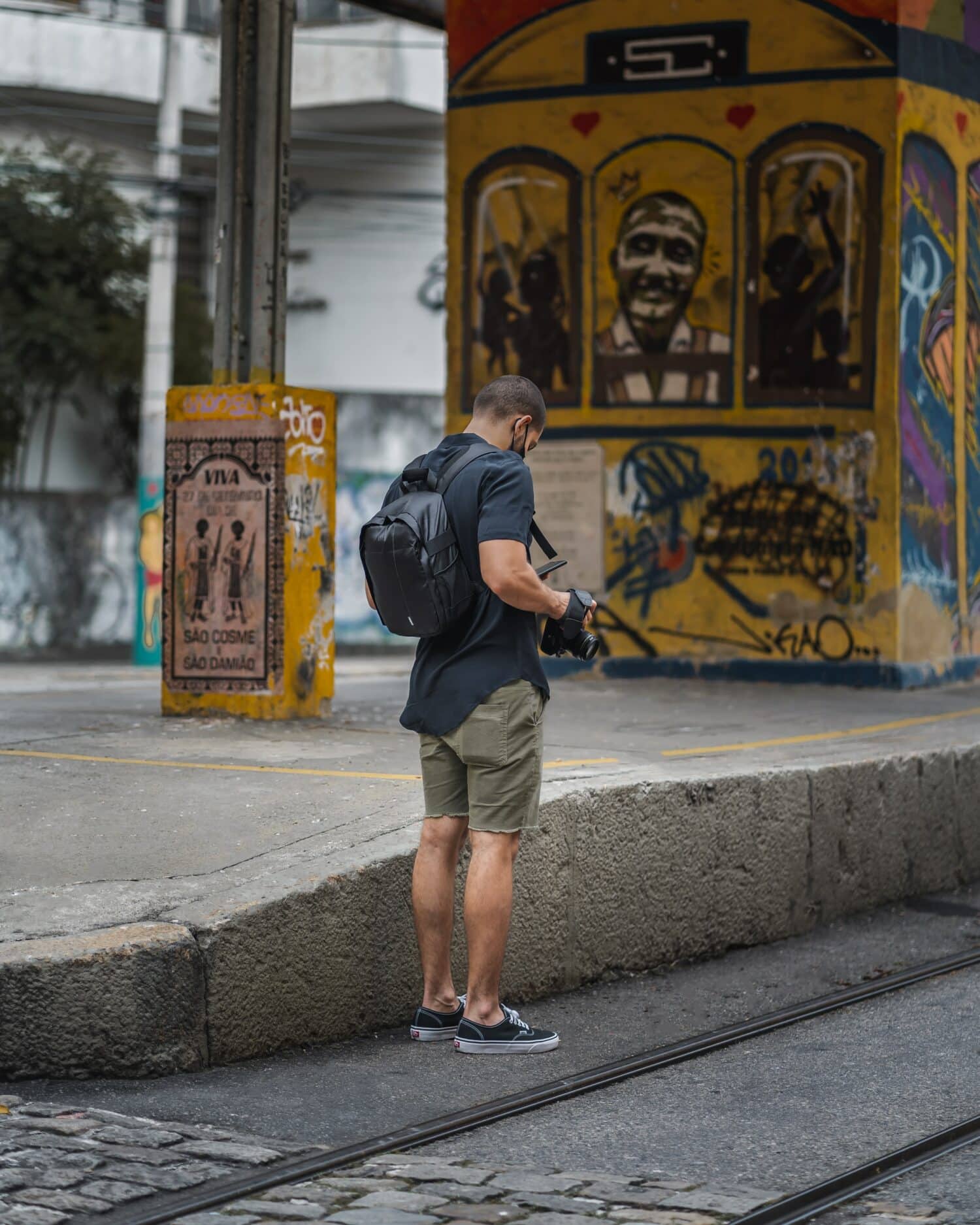 fotógrafo mexendo no celular em uma rua com muitos grafites, em Santa Teresa, Rio de Janeiro, para ilustrar o post chip internacional funciona no Brasil