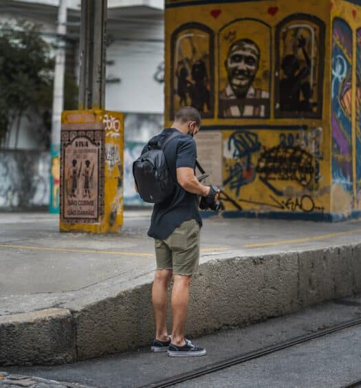 fotógrafo mexendo no celular em uma rua com muitos grafites, em Santa Teresa, Rio de Janeiro, para ilustrar o post chip internacional funciona no Brasil