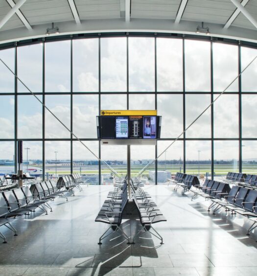 Saguão amplo do Aeroporto de londres Heathrow com uma janela enorme dando vista para a área de pouso dos aviões