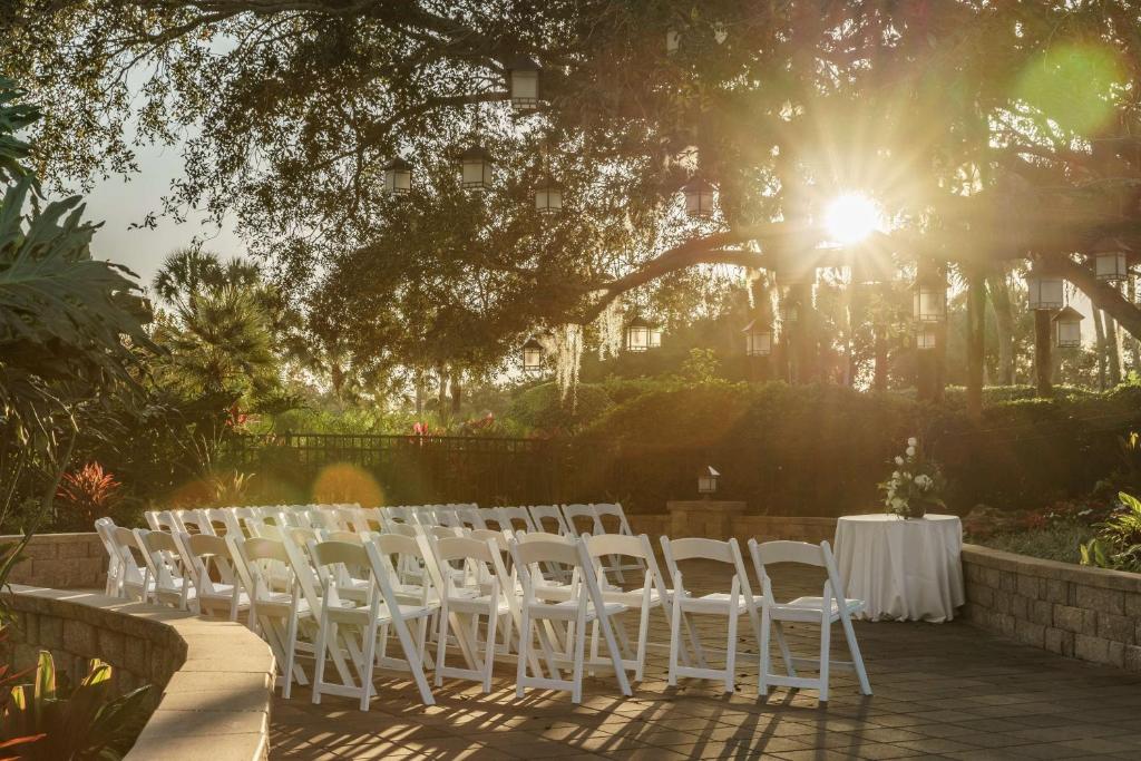 área comum que parece ser de eventos com cadeiras brancas, lanternas penduradas em uma árvore e uma mesa com toalha branca no Hyatt Regency Grand Cypress Resort, um dos hotéis românticos em Orlando