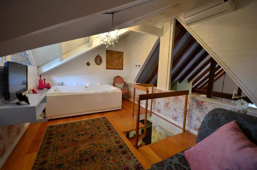área de estar no segundo andar de um dos quarto da Varanda das Bromélias SPA com uma banheira de hidromassagem, um sofá e uma televisão de tela plana