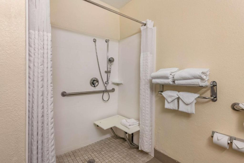 banheiro do Comfort Suites Maingate East com adaptações como barras de apoio, box de tecido, chuveirinho e cadeira de banho grudada na parede