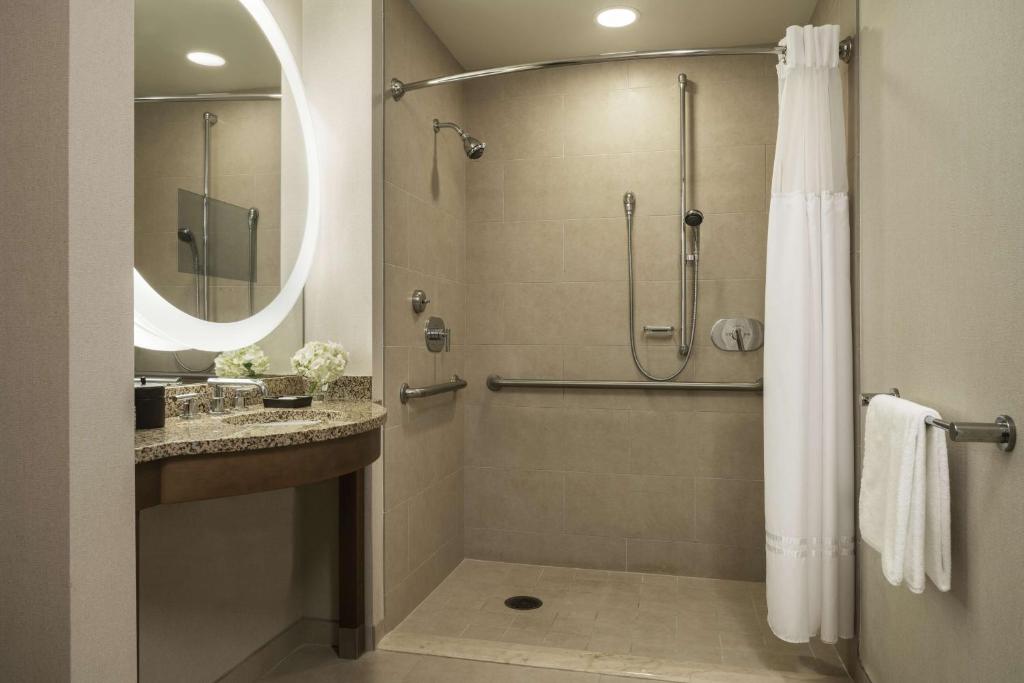 banheiro do Hyatt Regency Orlando com adaptações para PcDs como barras de apoio, box de tecido, chuveiriho e pia com abertura para cadeira de rodas