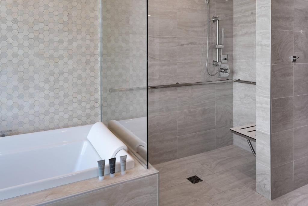 banheiro com banheira e box aberto com cadeira de banho, chuveirinho e barras de apoio no JW Marriott Orlando Bonnet Creek Resort & Spa um dos hotéis românticos em Orlando