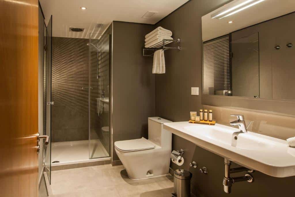 Banheiro com acessibilidade do Solace Hotel com bia baixa, vaso sanitário e box para o banheiro.