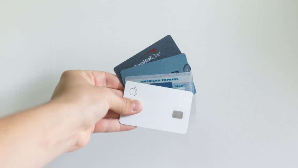 Mão segurando quatro cartões de crédito, para ilustrar um dos requisitos para o aluguel de carros em viagens