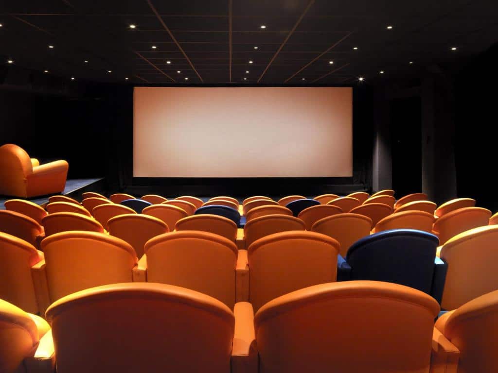 Uma pequena sala de cinema com poltronas laranjas e azuis, para representar hotéis boutique em Londres
