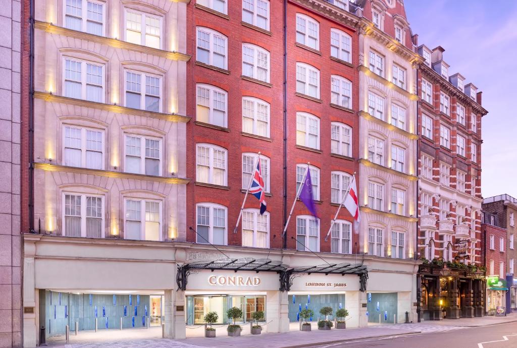 Prédio do Conrad London St James com  sete andares, em tons de tijolinhos branco e vermelho, há um hall de vidro com vasos de plantas, para representar hotéis perto do Big Ben em Londres