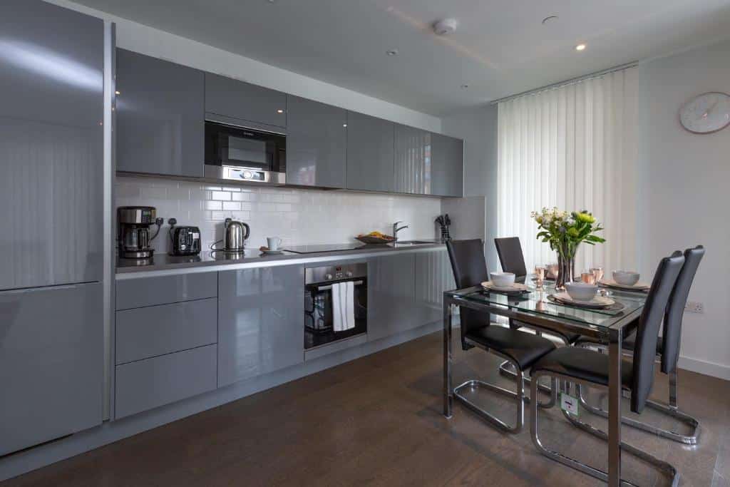 Cozinha do Deluxe Central London Apartment com uma mesa de quatro lugares, uma janela com persiana e piso de madeira, para representar aluguel de temporada em Londres