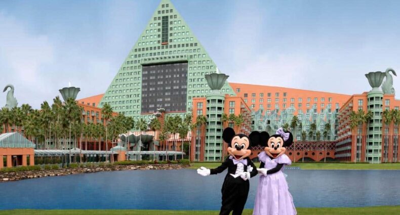 Mickey e Minnie em frente a um lago com a fachada do Walt Disney World Dolphin ao fundo, um dos melhores hotéis em Orlando
