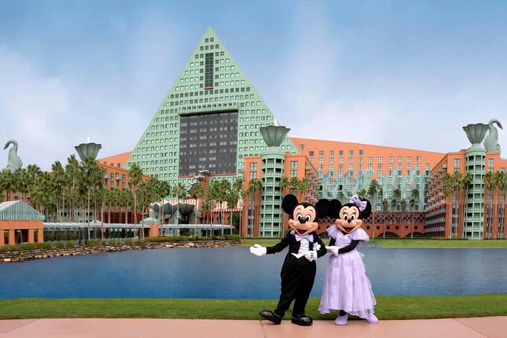 Mickey e Minnie em frente a um lago com a fachada do Walt Disney World Dolphin ao fundo, um dos hotéis em Orlando