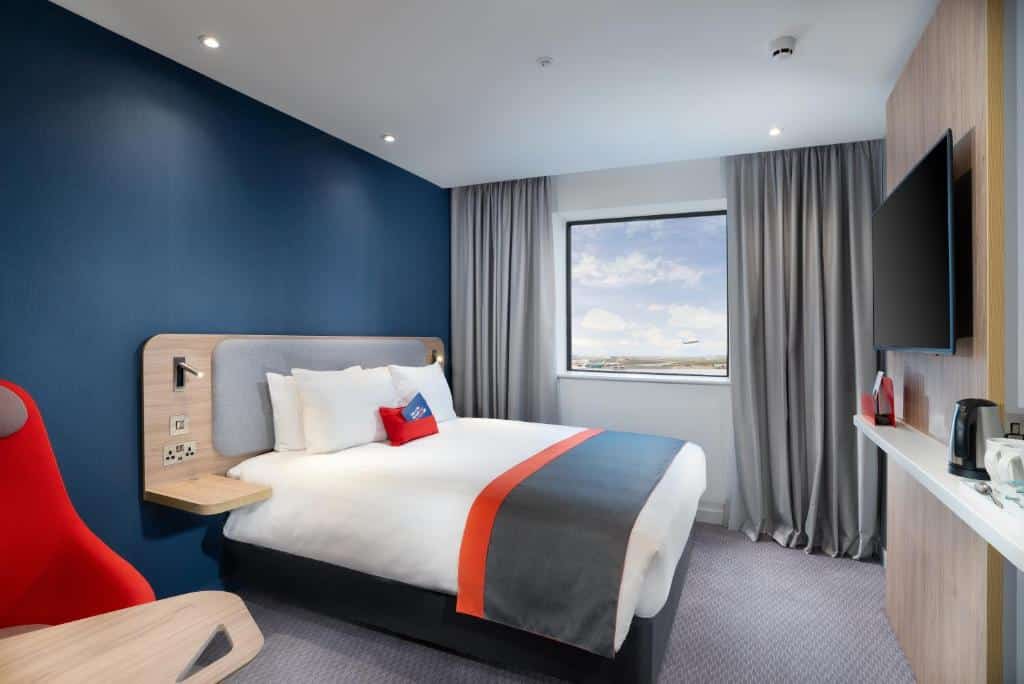 Quarto do Holiday Inn Express - London Heathrow T4, an IHG Hotel com uma janela com cortinas, uma cama de casal, uma televisão e uma poltrona, hotéis perto do Aeroporto de Londres Heathrow