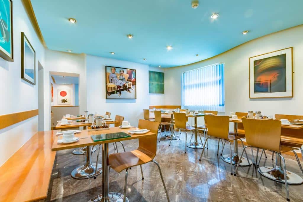Espaço para refeições do Luna And Simone Hotel com mesas e cadeiras de madeira, alguns quadros nas paredes e uma janela ampla com persiana, para representar hotéis para família em Londres