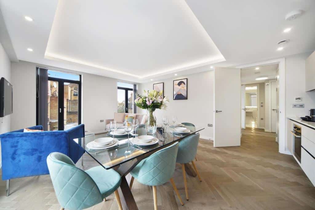 Sala ampla no Lux Apartments in Fulham by Dino com uma mesa com quatro lugares, uma cozinha, uma porta de vidro para um terraço, um sofá, uma poltrona e uma televisão