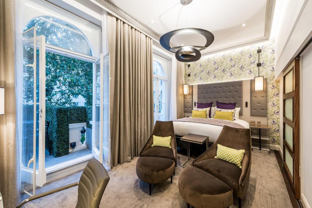 Quarto no Mercure London Hyde Park Hotel com uma cama de casal, duas poltronas, uma varanda que leva para um pequeno jardim, chão de carpete, tudo decorado em tons de marrom, para representar hotéis Mercure em Londres