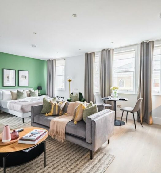 Sala de estar do No. 2 Queensberry Place by Stayo com janelas amplas com cortinas, um sofá, piso de madeira, uma parede verde com quadros pendurados, uma mesa de centro e tudo decorado de um jeito moderno, para representar aluguel de temporada em Londres