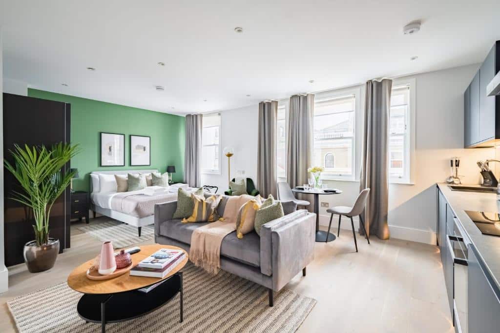 Sala de estar do No. 2 Queensberry Place by Stayo com janelas amplas com cortinas, um sofá, piso de madeira, uma parede verde com quadros pendurados, uma mesa de centro e tudo decorado de um jeito moderno, para representar hotéis em Londres para brasileiros