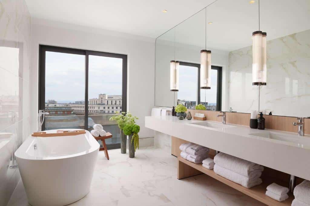 Banheiro amplo do Nobu Hotel Londres Portman Square com uma janela ampla, uma banheira oval, uma pia com duas cubas e um espelho amplo