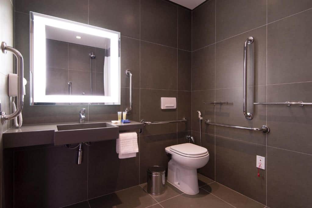 Banheiro adaptado do Novotel São Paulo Berrini com barras de apoio, pia mais baixa e box sem vidro