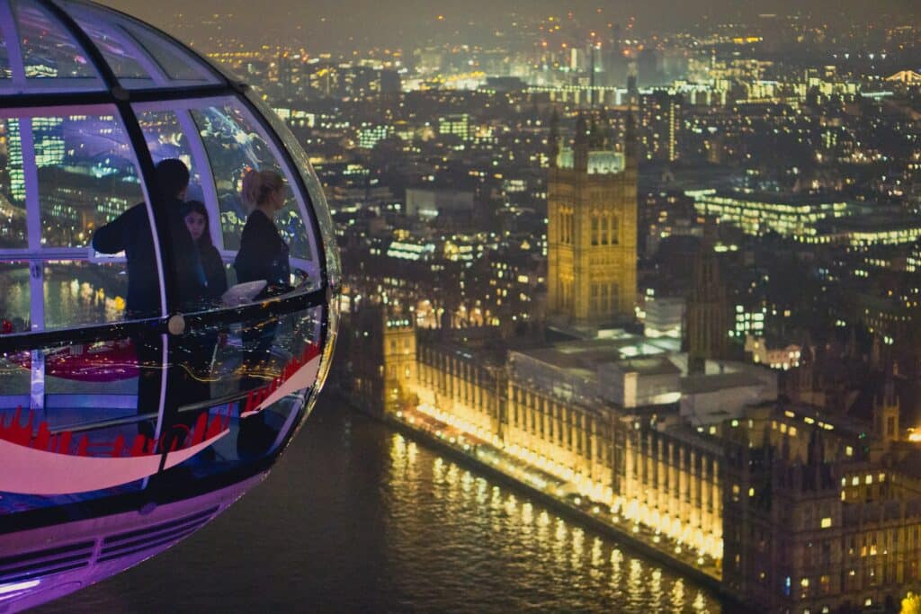 Uma das cabines da London Eye com pessoas dentro observando toda a cidade iluminada de noite