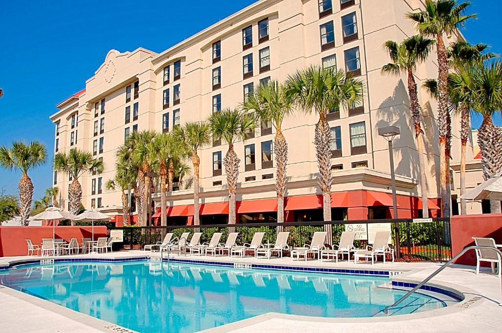 fachada em tons bege com palmeiras enfileiradas do Hampton Inn Orlando-Convention Center um dos hotéis na International Drive em Orlando, com piscina abaixo