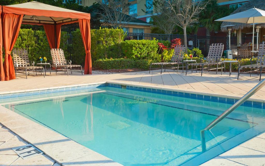 piscina retangular com gazebo e cadeiras e a fachada do Hilton Garden Inn Orlando International Drive North, um dos hotéis na International Drive em Orlando