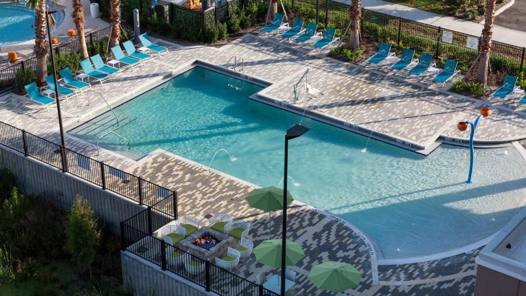 piscina do Holiday Inn Express & Suites - Orlando At Seaworld, an IHG Hotel, um dos hotéis na International Drive em Orlando, grande com cadeiras ao redor e algumas palmeiras