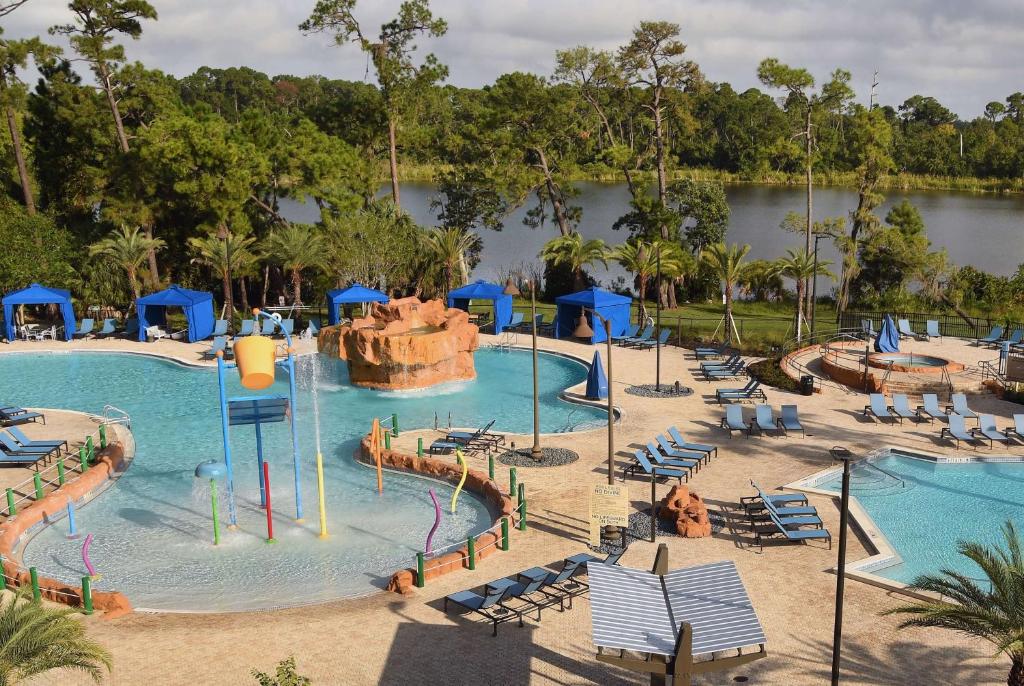 vista do lago além das piscinas com parque aquático e cachoeira com cadeiras ao redor no Wyndham Lake Buena Vista Resort Disney Springs® Resort Area, um dos hotéis perto de Lake de Buena Vista em Orlando