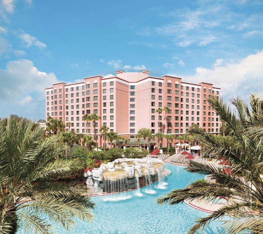 cachoeiras e cascatas com palmeiras ao redor que desemboca em uma grande piscina, com a fachada imponente atrás do Caribe Royale Orlando, um dos hotéis perto de Lake Buena Vista em Orlando