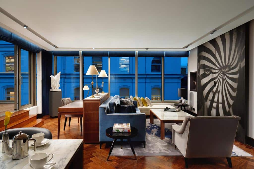 Sala de estar do Hilton London Bankside com uma janela panorâmica, sofás, poltronas, e uma mesa para refeições
