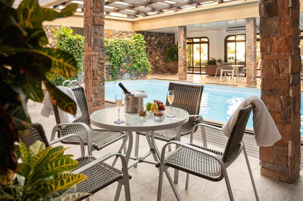piscina coberta do Serrazul Hotel Distributed By Intercity com uma mesa redonda de inox no lado de fora, acompanhada de quatro cadeiras. Em cima da mesa há um balde com champanhe e duas taças ao lado.