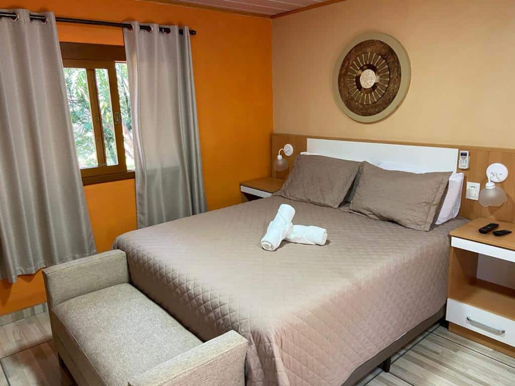 quarto da Pousada Maibe Amanhecer na Serra com uma cama de casal, duas cômodas com lâmpadas de cada lado da cama e uma janela à esquerda do quarto.