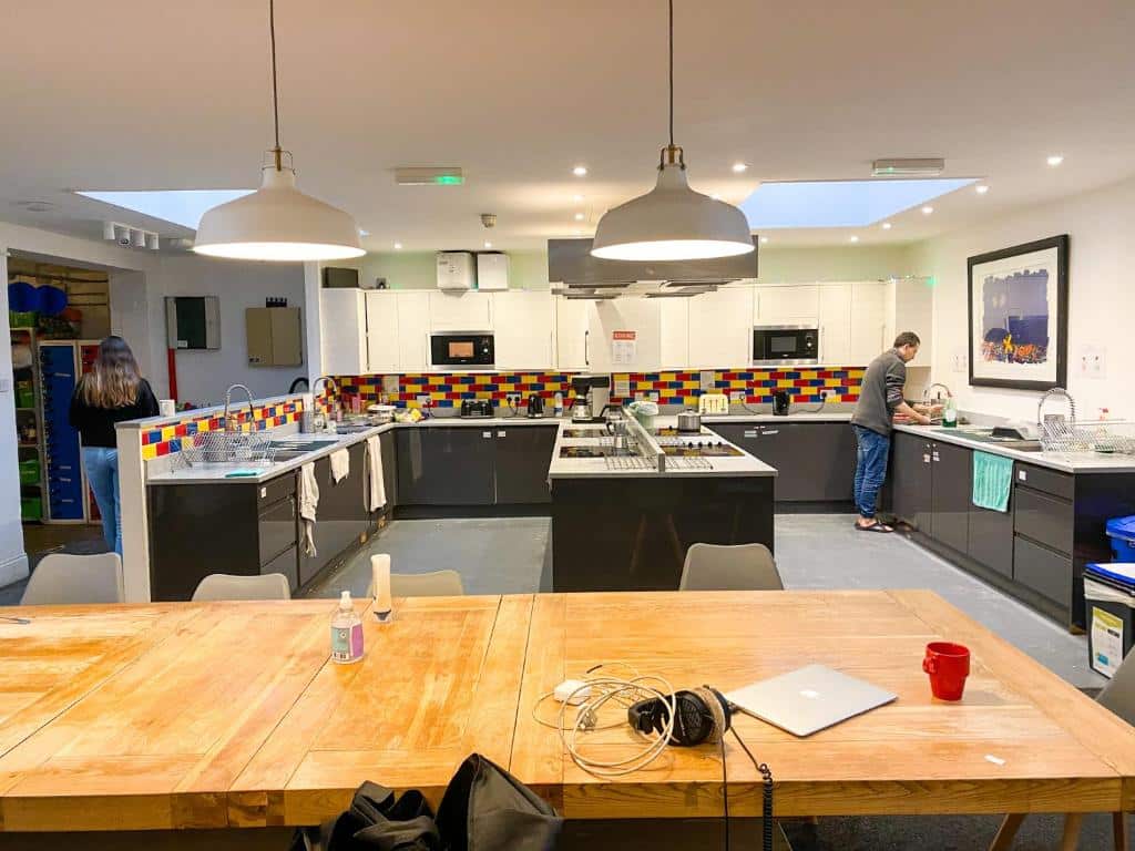 Cozinha compartilhada do Prime Backpackers Angel com quatro pias, quatro fogões, bancadas extensas e uma grande mesa para refeições, para representar hostels em Londres