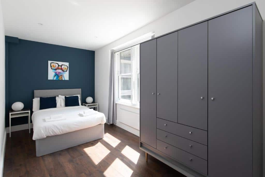 Quarto do homely – Central London Liverpool Street Apartments com janela com cortinas, um armário, uma cama de casal e o chão é de madeira, para representar airbnb em Londres