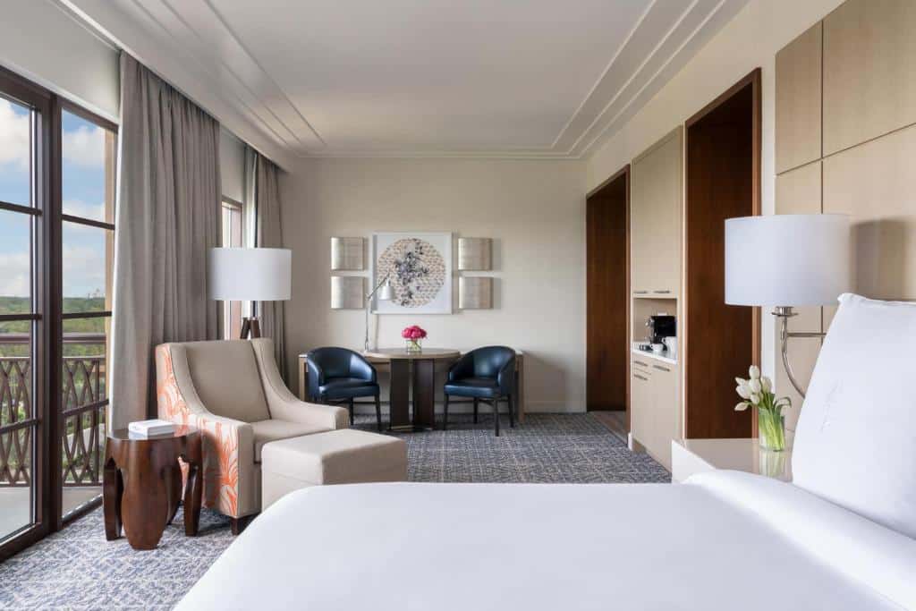 quarto do Four Seasons Resort Orlando, um dos hotéis românticos em Orlando com cama grande casal, poltrona com mesinha e mais cadeiras confortáveis com mesinha e varanda com vista
