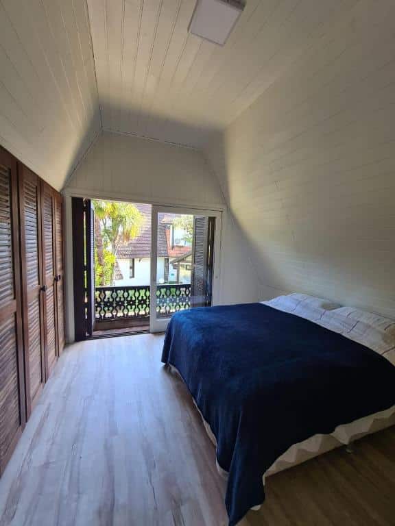 quarto do Chalé do Bosque com uma cama de casal e uma varanda privativa com vista para o quintal