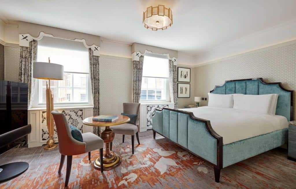 Quarto do Great Scotland Yard Hotel, part of Hyatt com uma cama de casal, duas janelas com cortinas, carpete no chão, uma mesa redonda com duas cadeiras e uma televisão