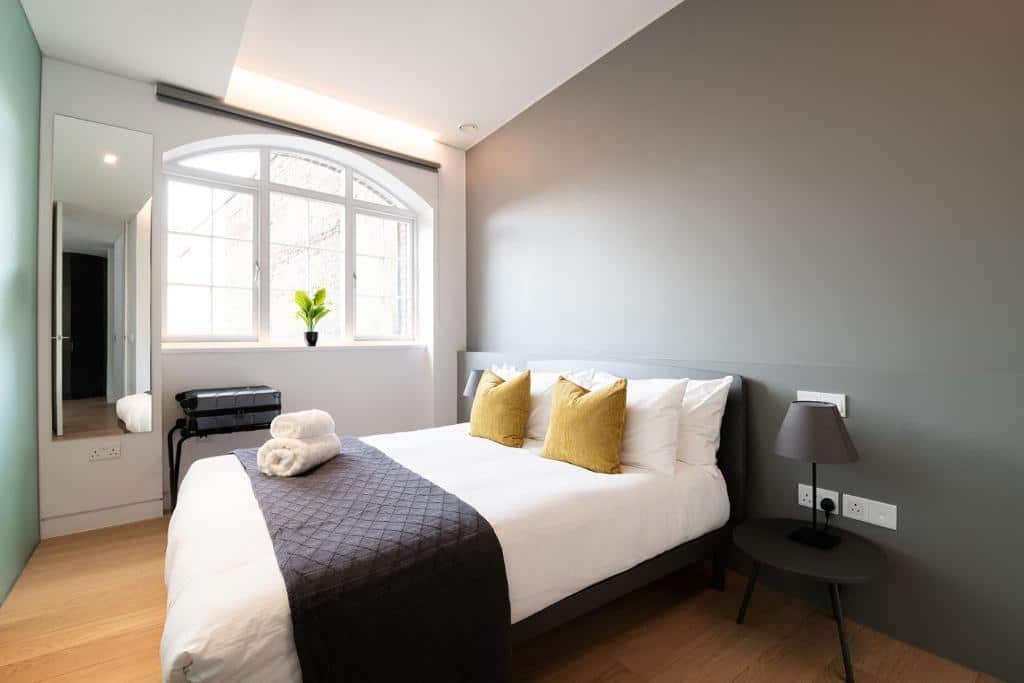 Quarto do Mirabilis Apartments - Bayham Place com uma cama de casal, uma janela, um espelho e duas mesinhas de cabeceira com abajures