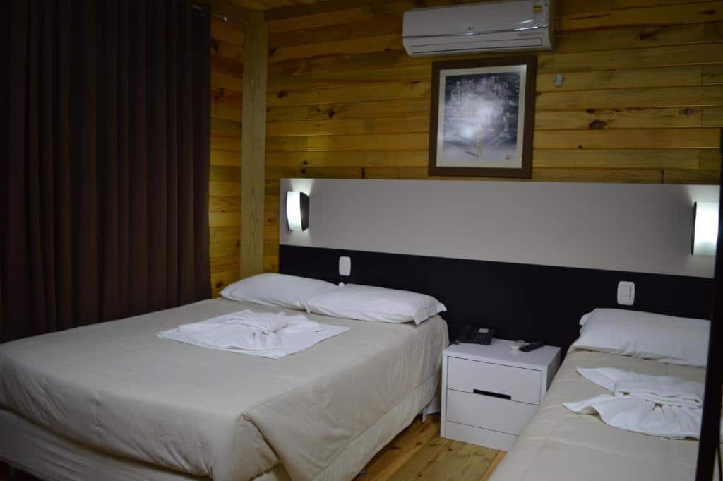 quarto dos Chalés da Montanha com uma cama de casal à esquerda e uma cama de solteiro à direita.