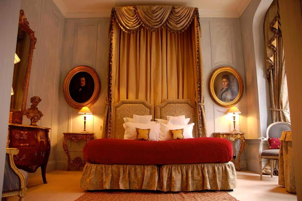 Quarto luxuoso do San Domenico House com uma cabeceira em tecido que vai até o teto, uma cama de casal, poltronas, móveis de época e alguns quadros nas paredes